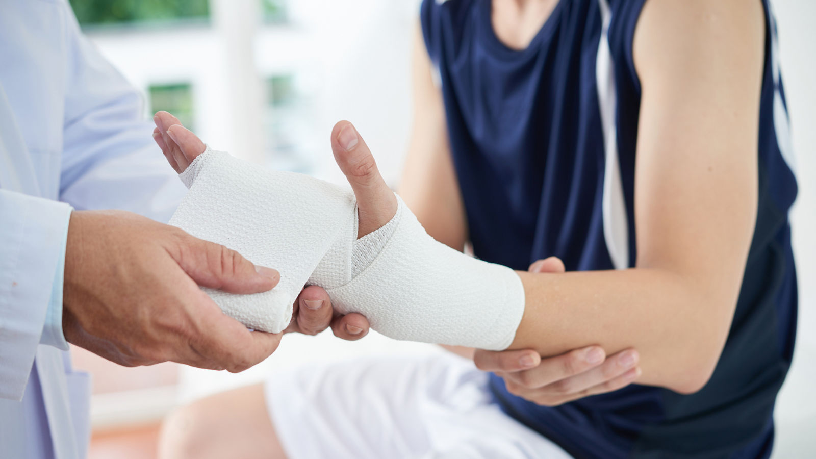 Unrecognizable doctor dressing injured hand of patient