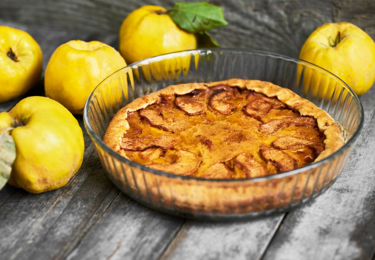 Homemade apple quince pie on rustic wooden background.