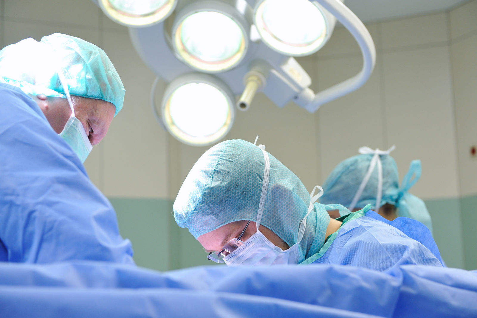 Operateure stehen am OP-Tisch mit OP-Kleidung und Masken