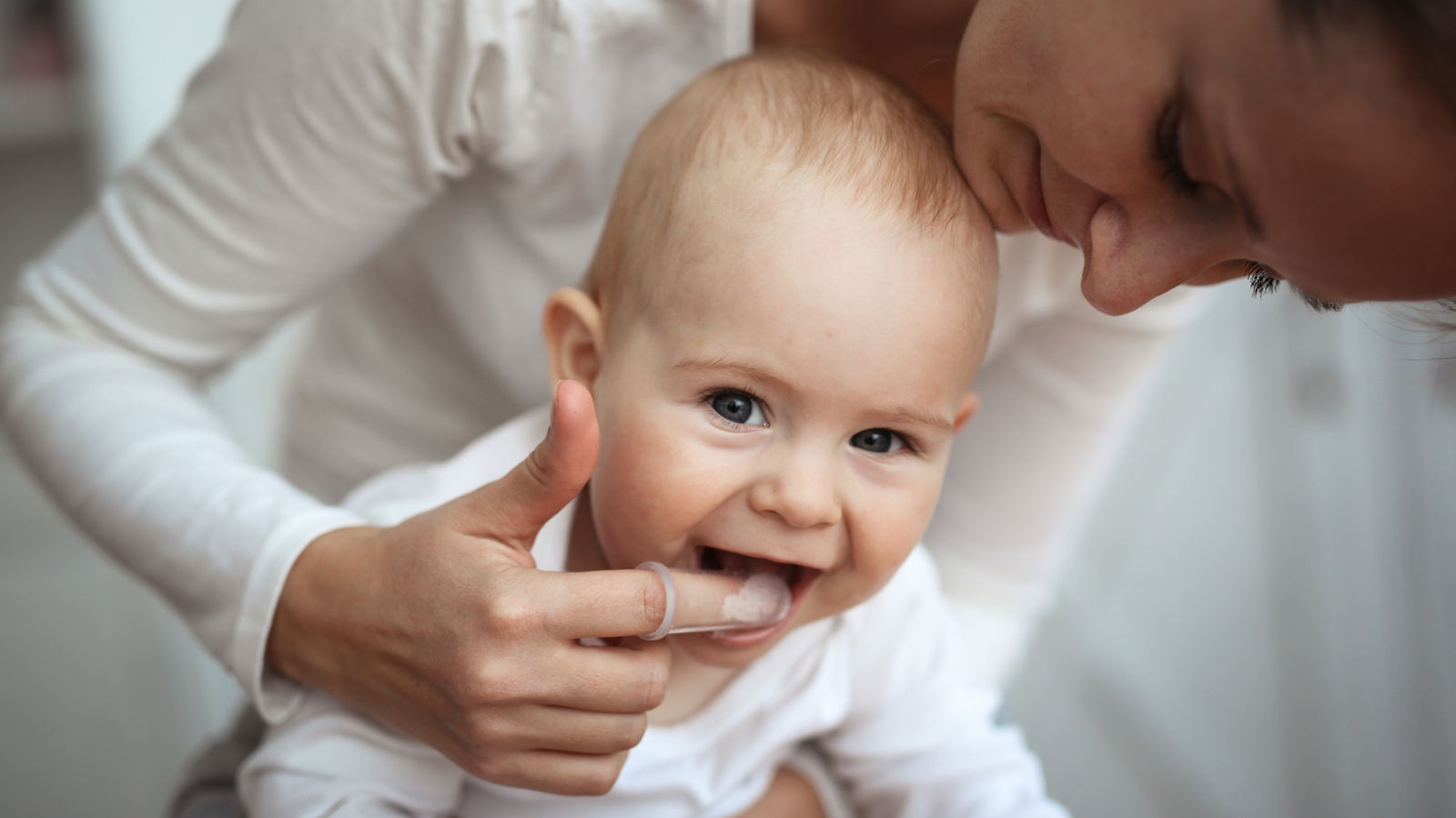 Mom helps to brush teeth of happy baby, Hygiene