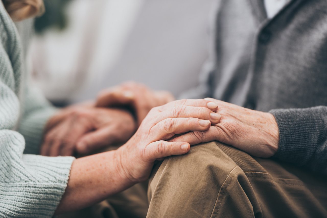 cropped view of retired couple holding hands 