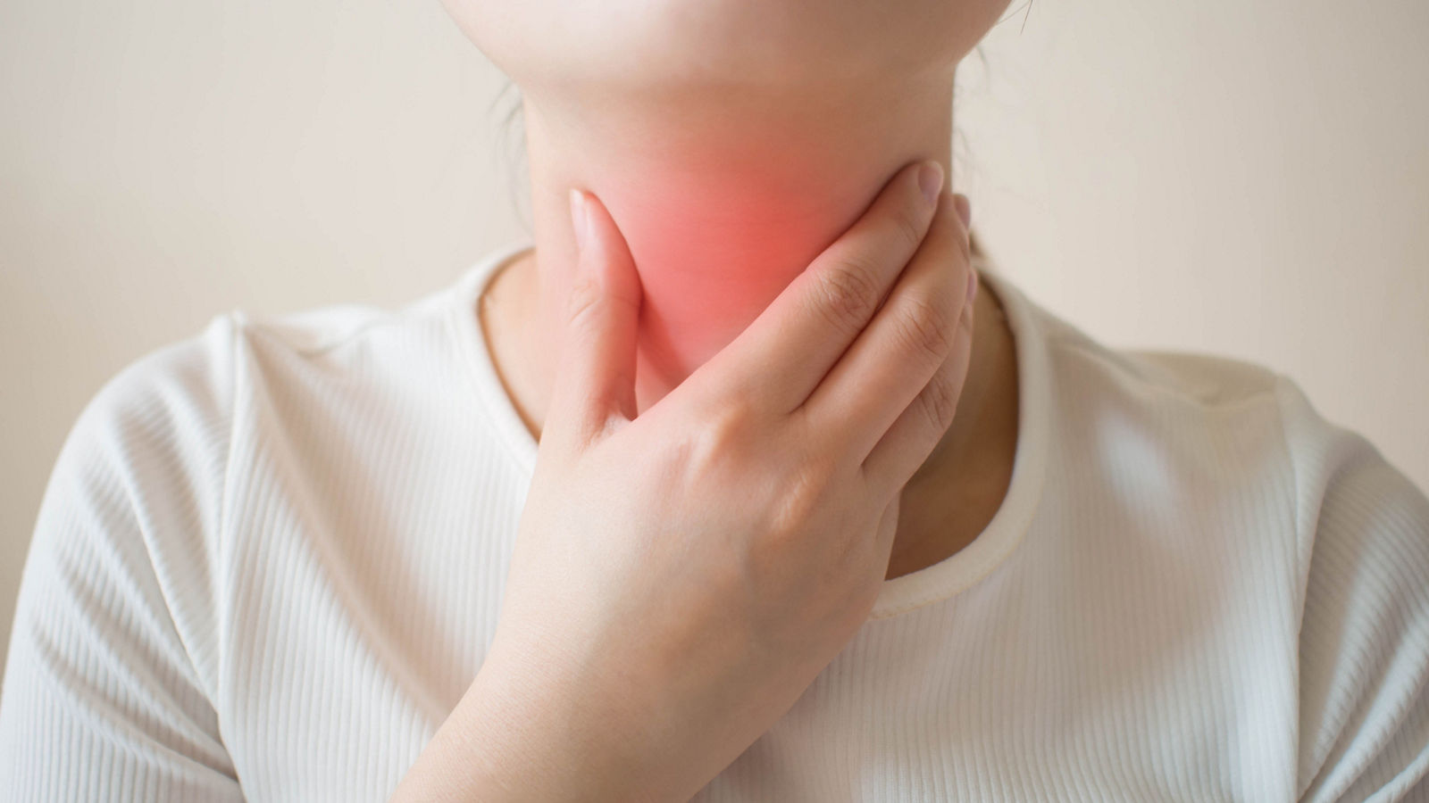 Sick women suffering from sore throat on gray background. Causes of throat pain include flu, common cold, bacterial infections, allergies, smoke, GERD or tumor. Health and medical concept. Close up.