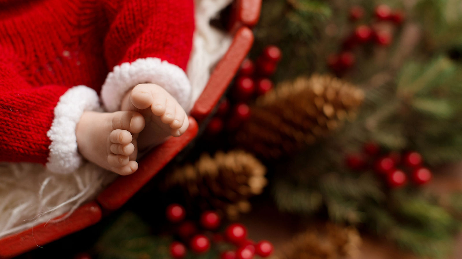 The steps of a newborn baby on a background with christmas decorations.  Little Santa 