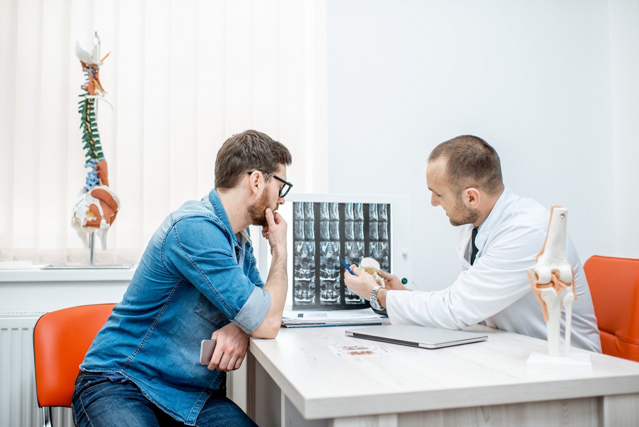 Man during the medical consultation with senior therapist looking on the tomography print at the office