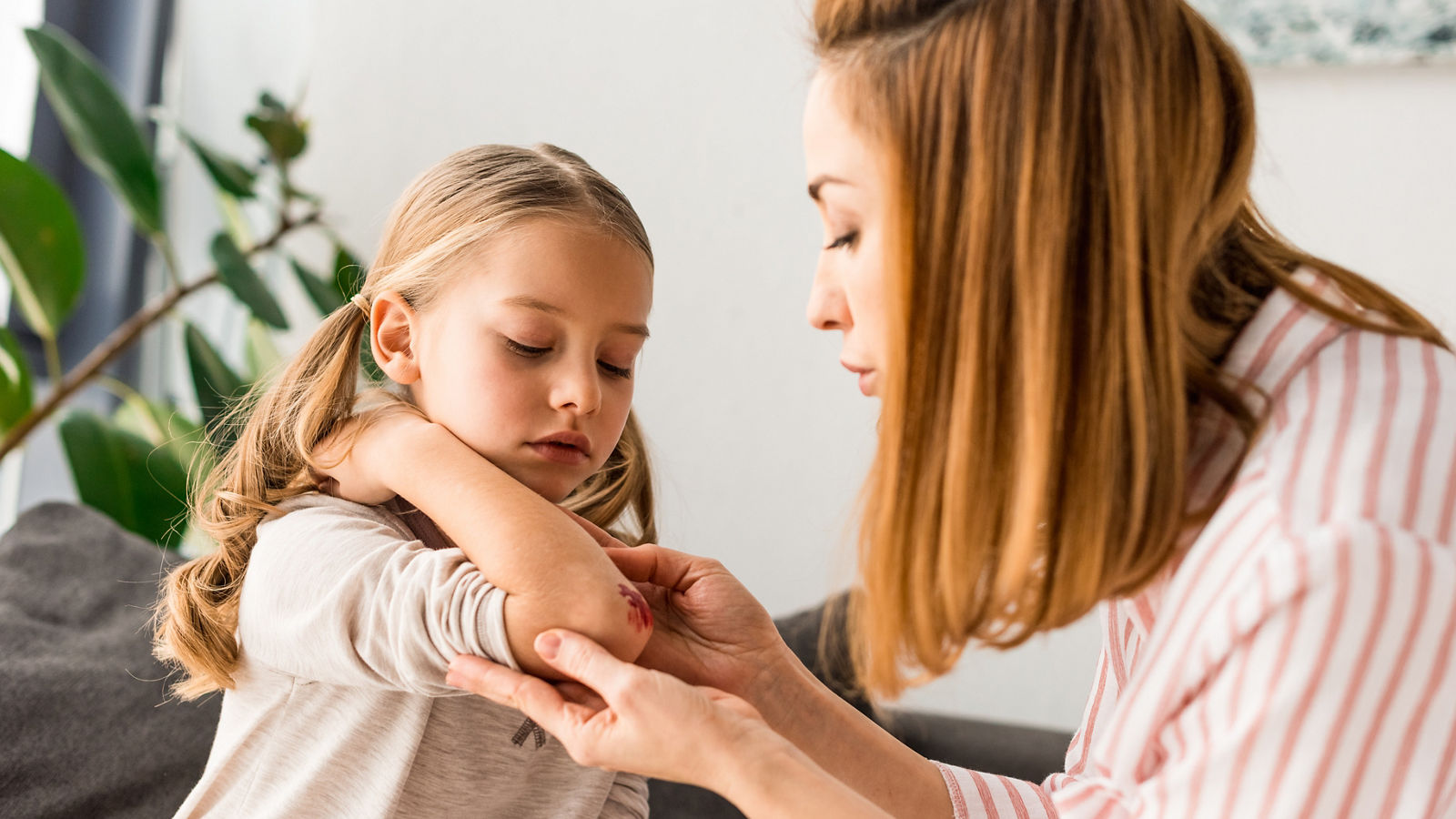 Attractive mother caring injured daughter at home