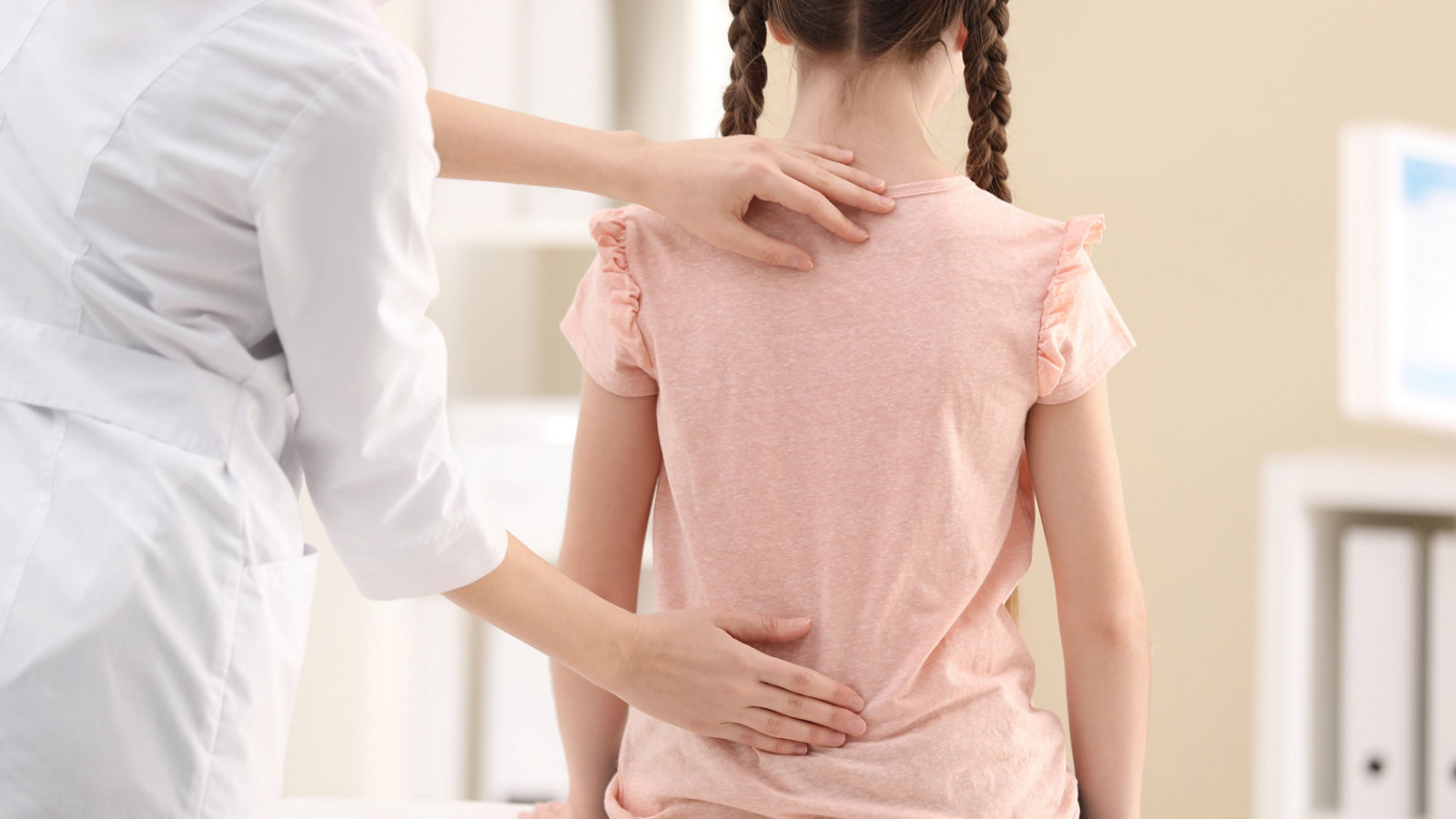 Chiropractor examining child with back pain in clinic, closeup