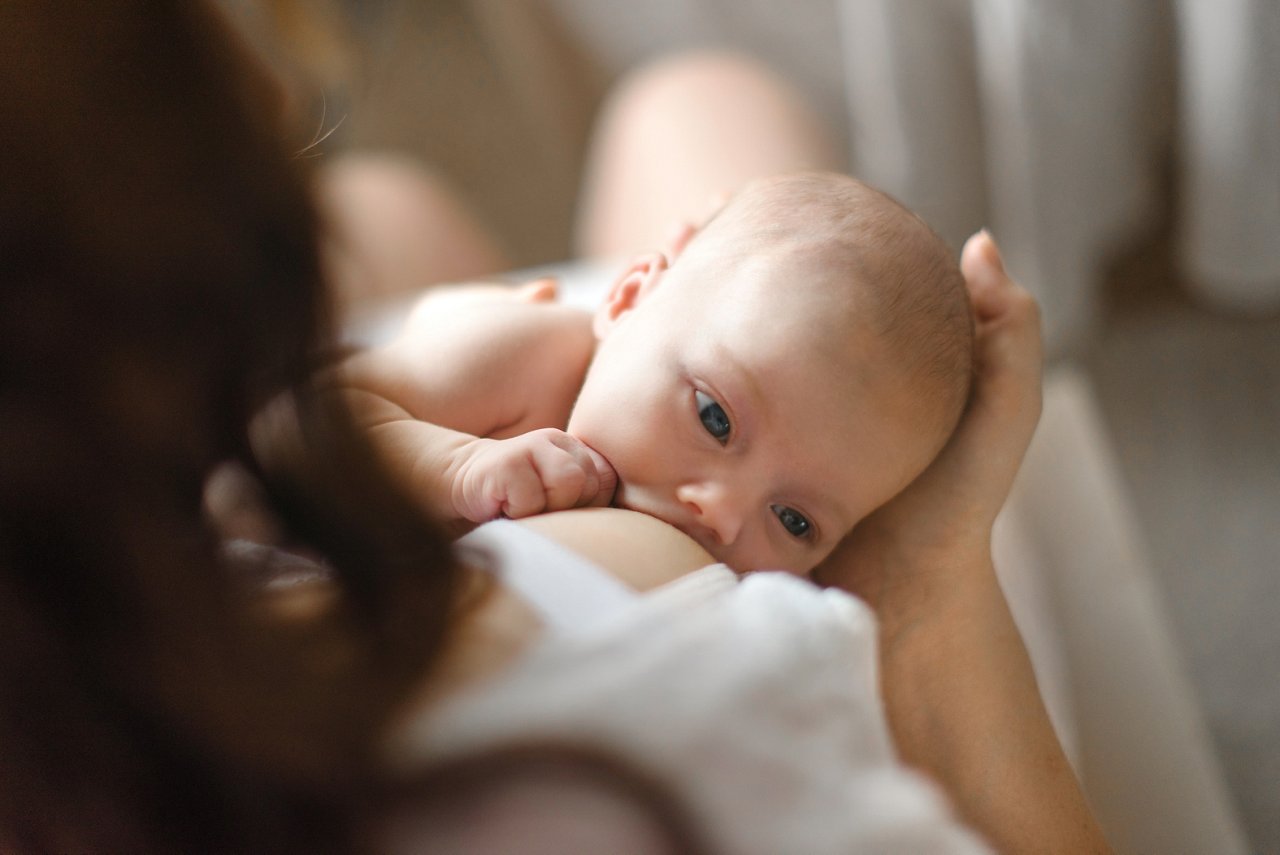 Breast-feeding. Red-haired beautiful mother breastfeeds a newborn baby. Lifestyle