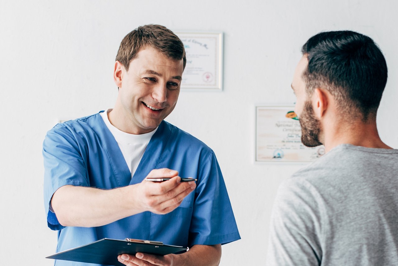 panoramic shot of smiling Physiotherapist with diagnosis near patient in hospital