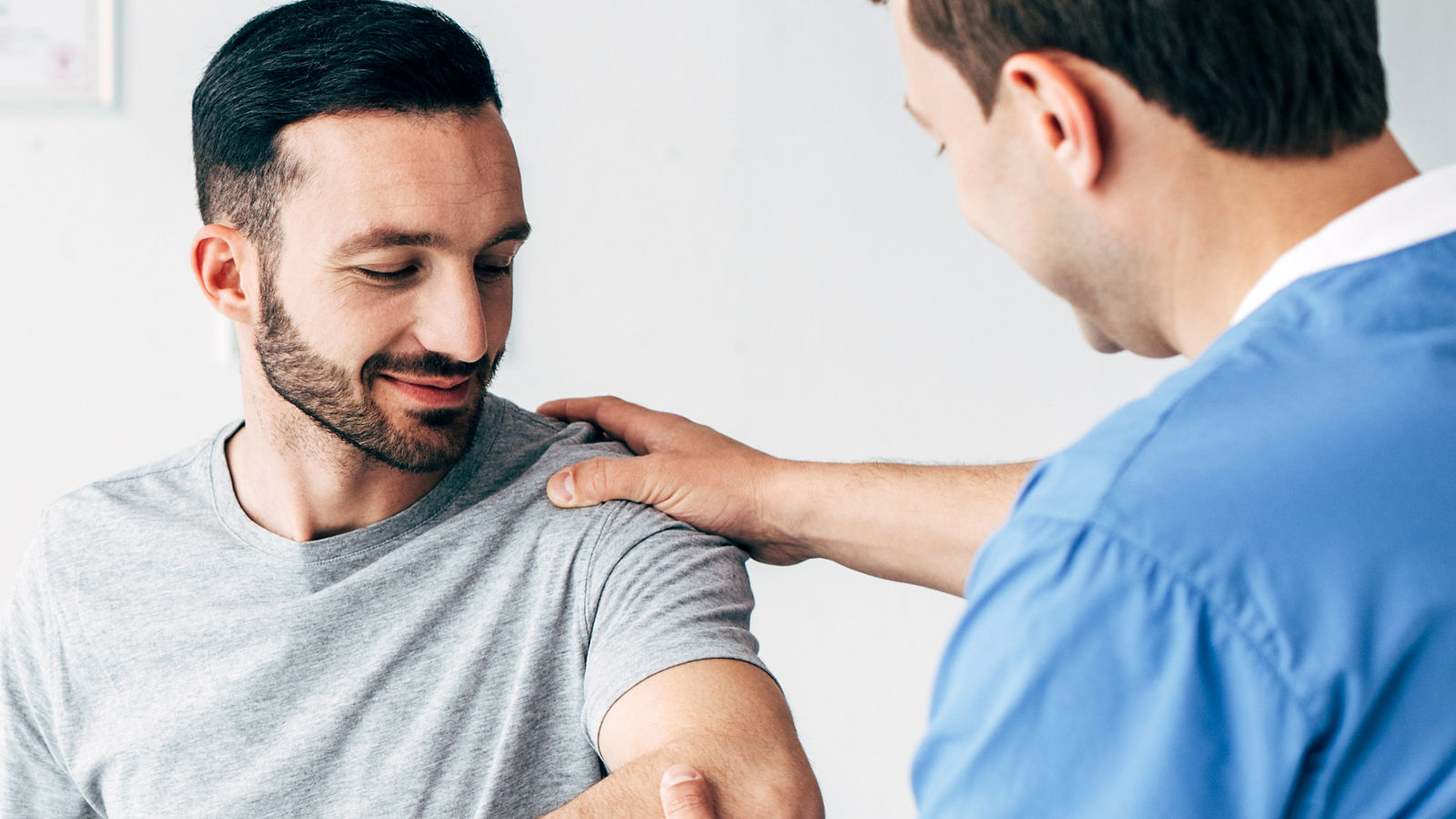 panoramic shot of chiropractor massaging arm of patient in hospital with copy space