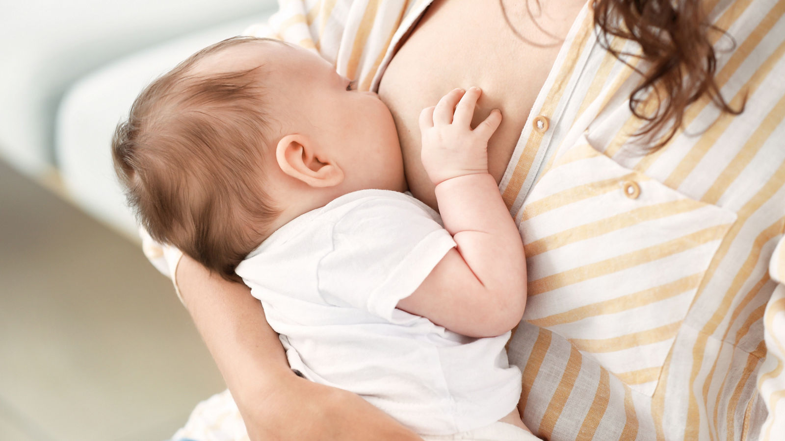 Young woman breastfeeding her baby at home