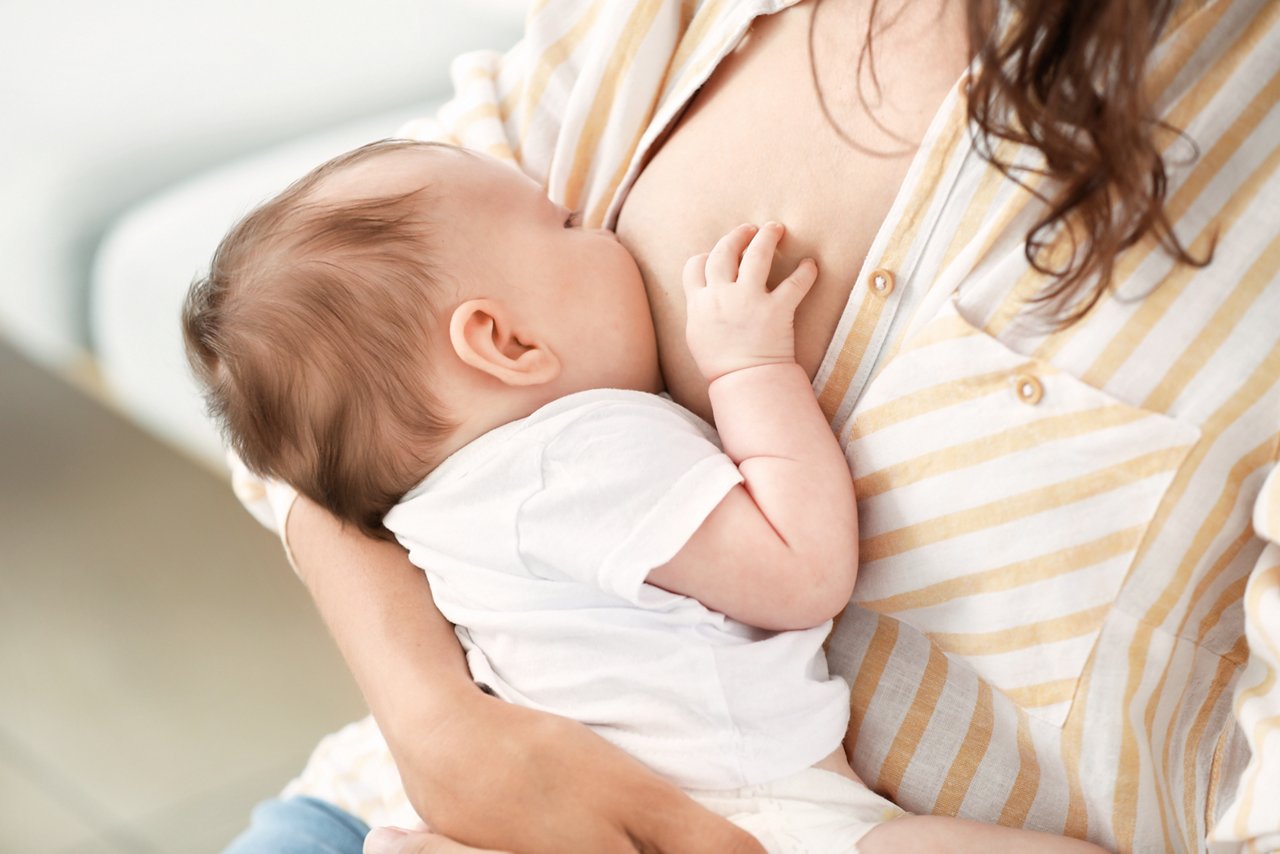 Young woman breastfeeding her baby at home