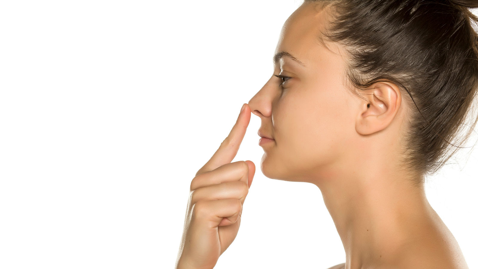 young woman touches her nose with her finger on a white background