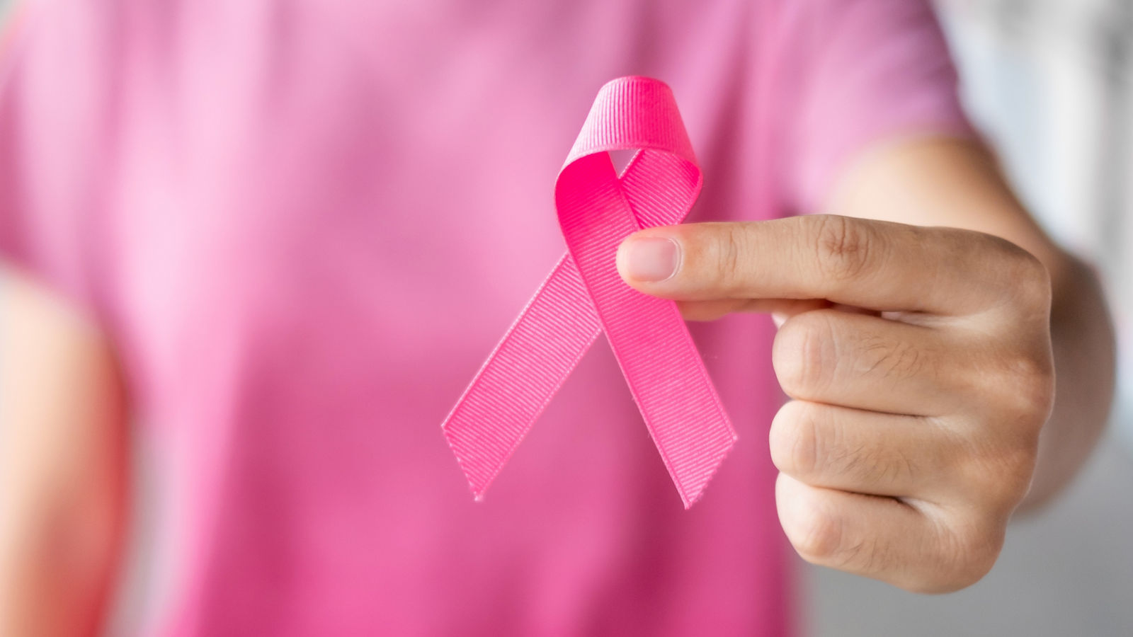 October Breast Cancer Awareness month, Woman in pink T- shirt with hand holding Pink Ribbon for supporting people living and illness. Healthcare, International Women day and World cancer day concept