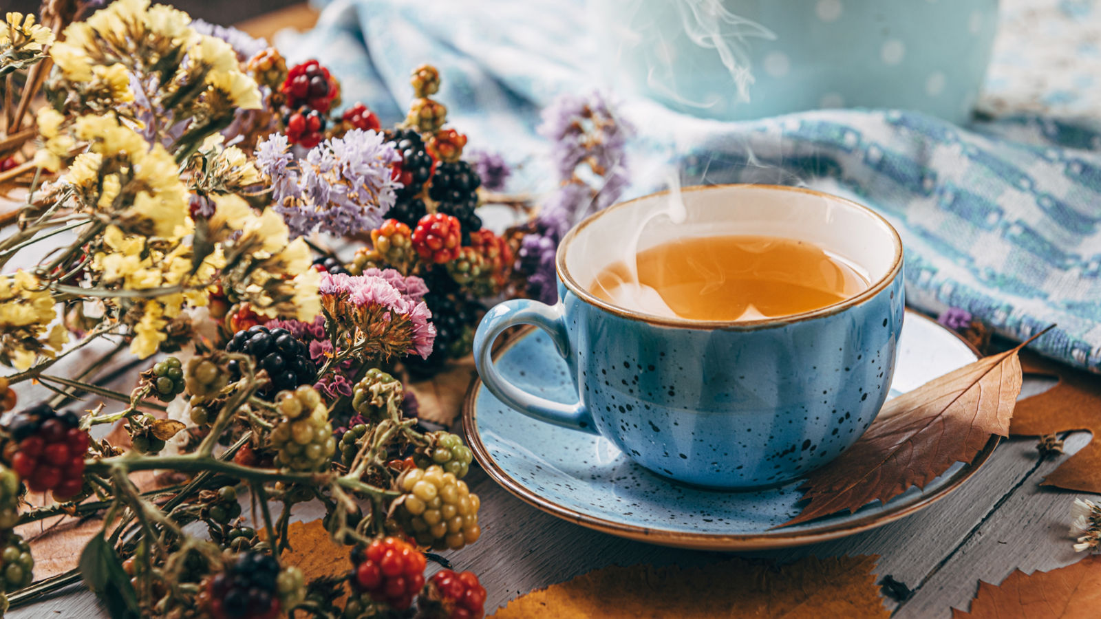 autumn warming tea on a wooden table with autumn tree leaves lying nearby
