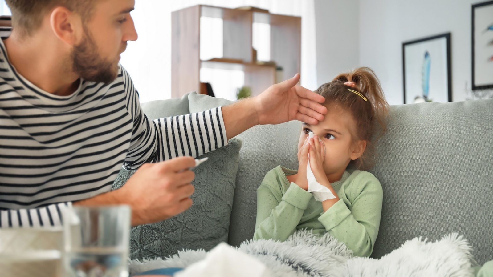 Father taking care of his daughter ill with flu at home