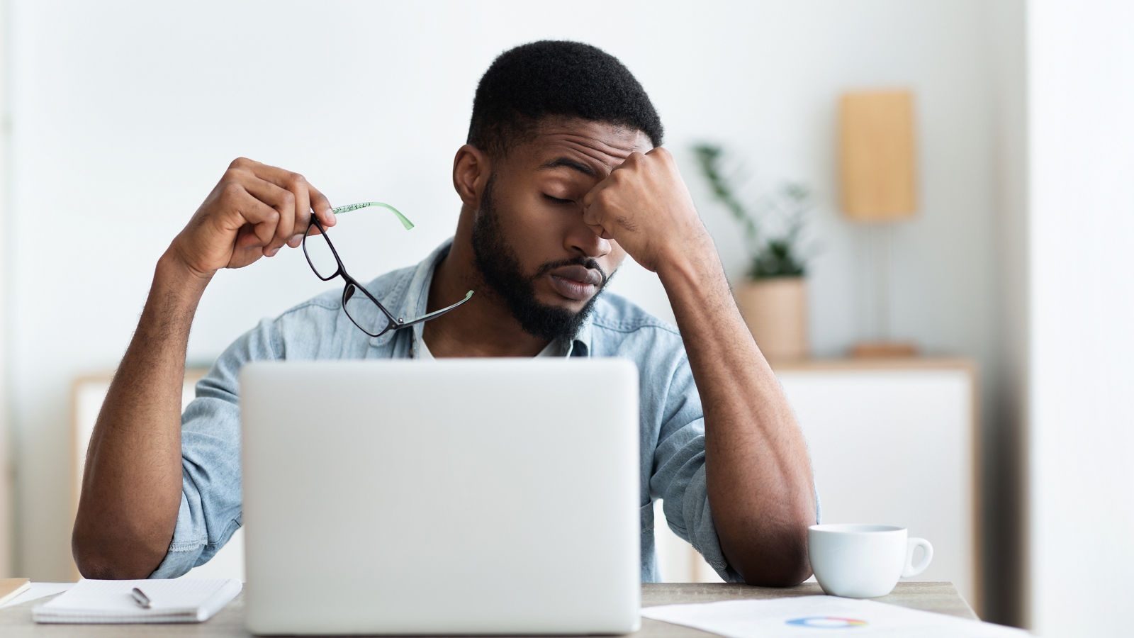 Tired african american employee having headache after working on laptop