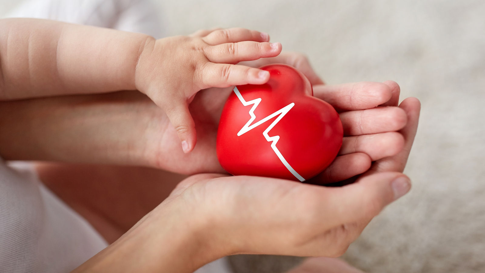 baby and mother holding red heart with ecg line