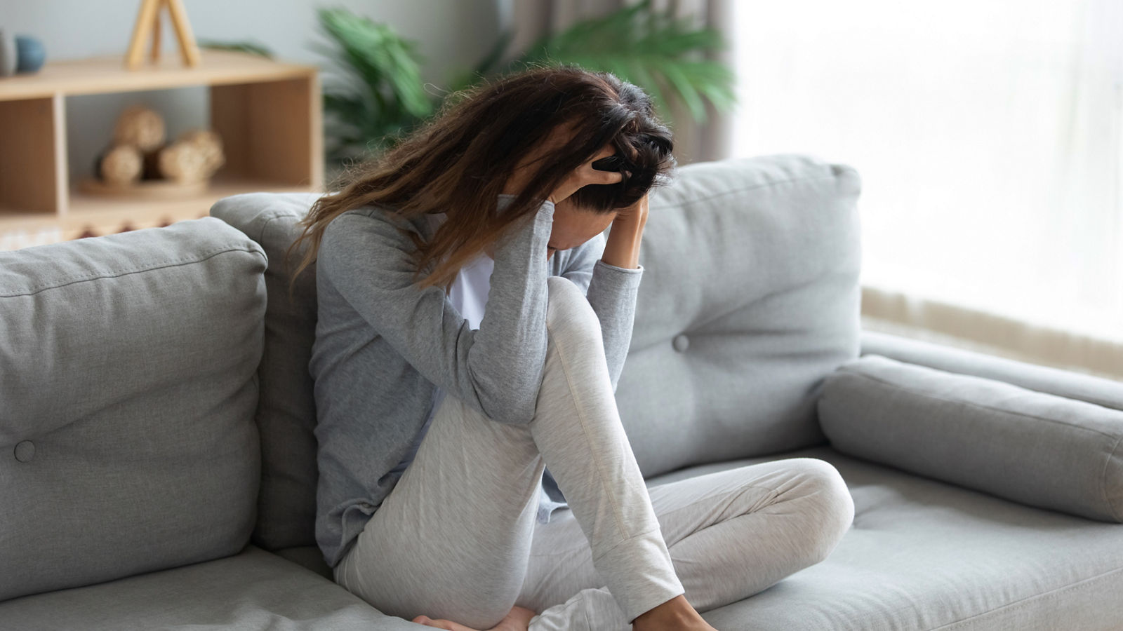 Stressful young mixed race woman holding head in hands.