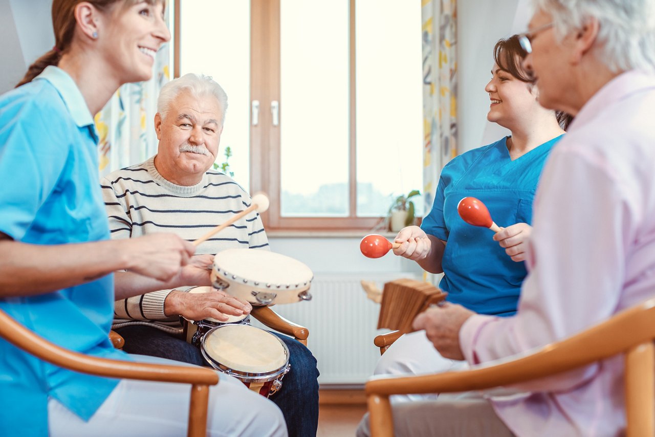 Seniors in nursing home making music with rhythm instruments as musical therapy