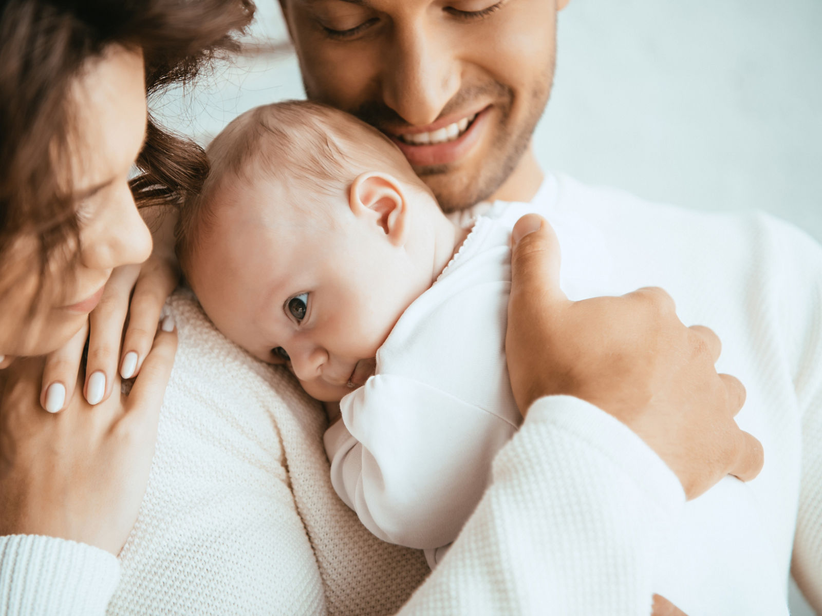 cropped view of happy man holding adorable baby near smiling wife