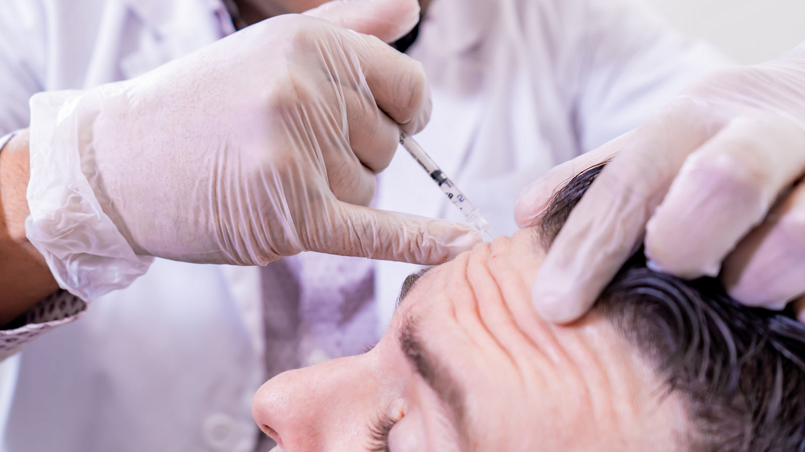 Caucasian man undergoing beauty spa botulinum neurotoxin Botox treatment for anti-aging, to smooth wrinkles as a cometic solution. Injecting forehead to relax muscles with a non-invasive procedure.