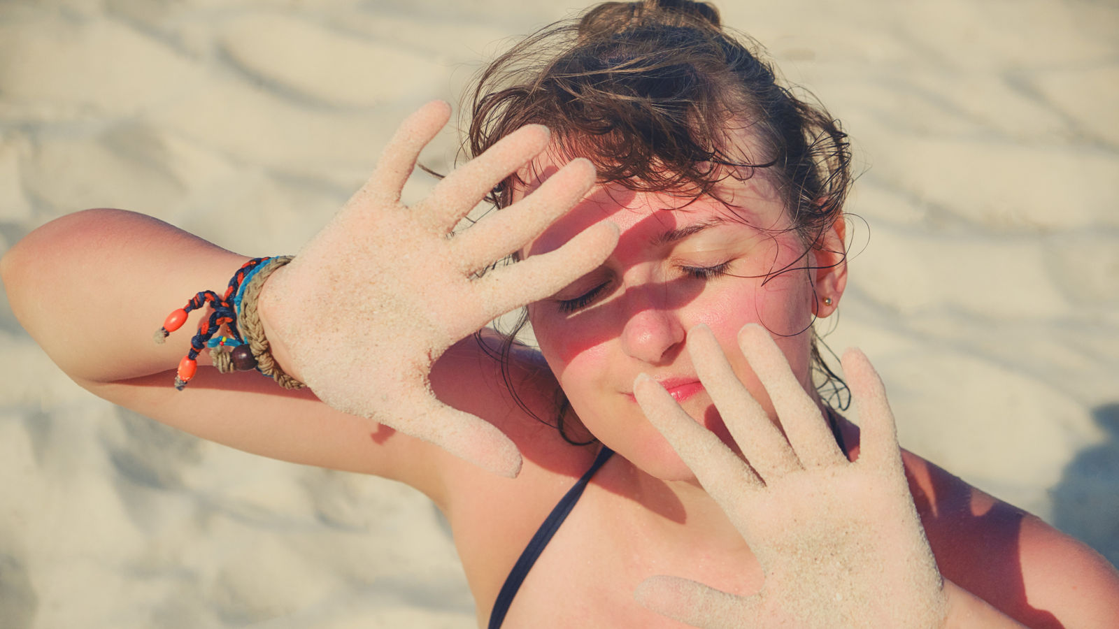 Girl put her hands in front of her face for protection from the sun.