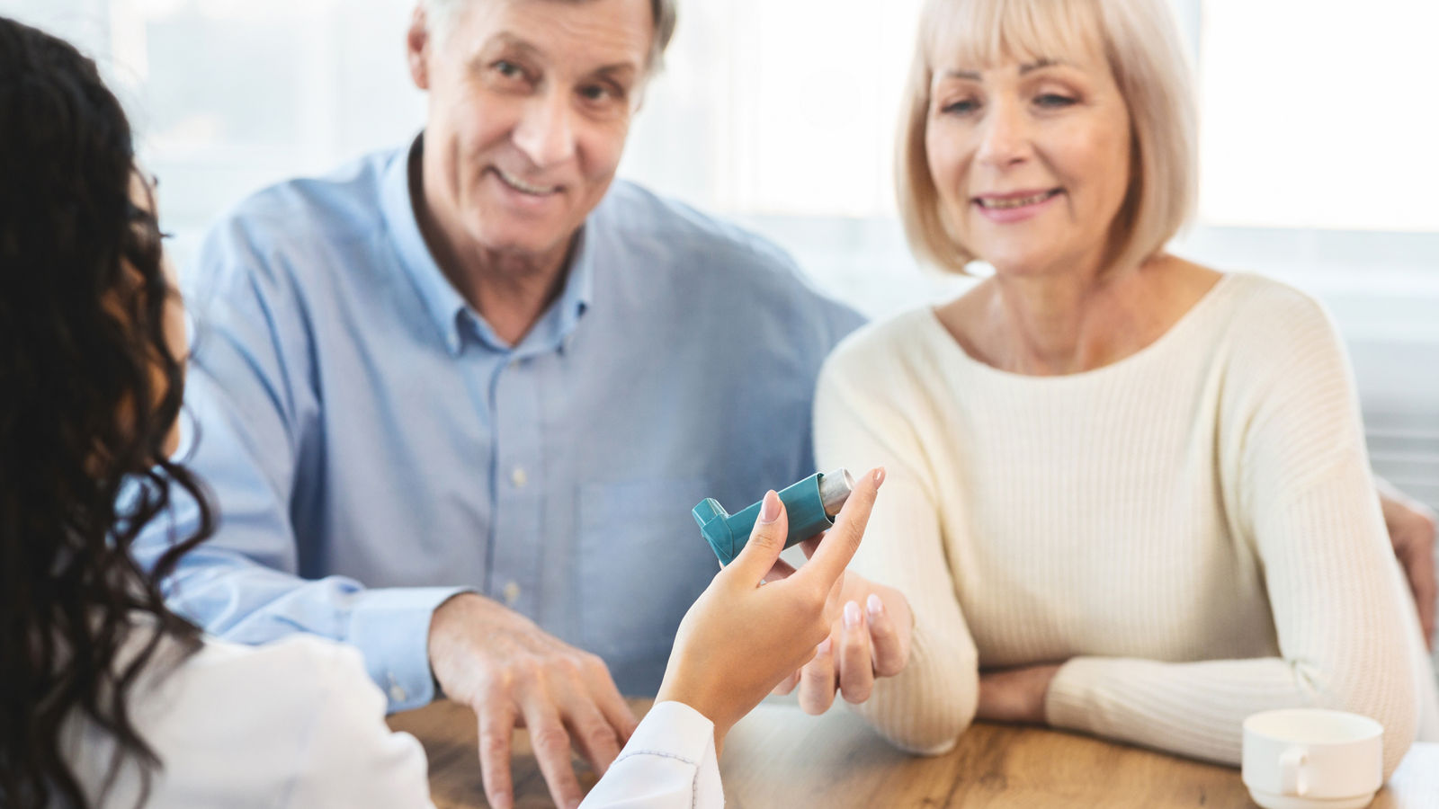 Female physician giving asthma inhaler to senior patients