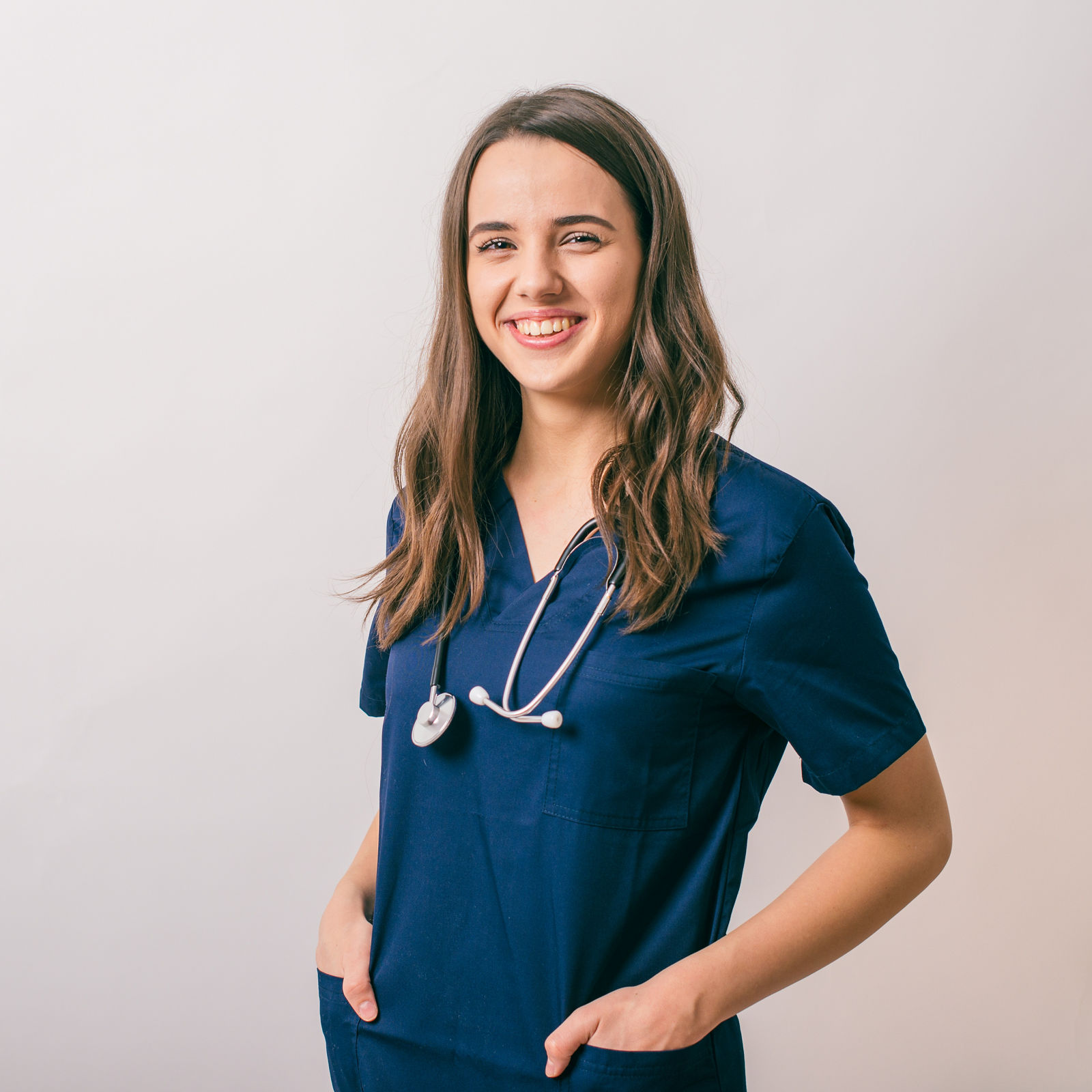 cheerful young female doctor with stethoscope over neck looking at camera isolated on white