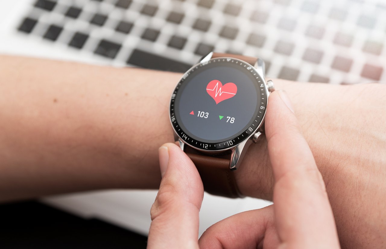 Hands with heart icon on smartwatch. Heart rate measurement