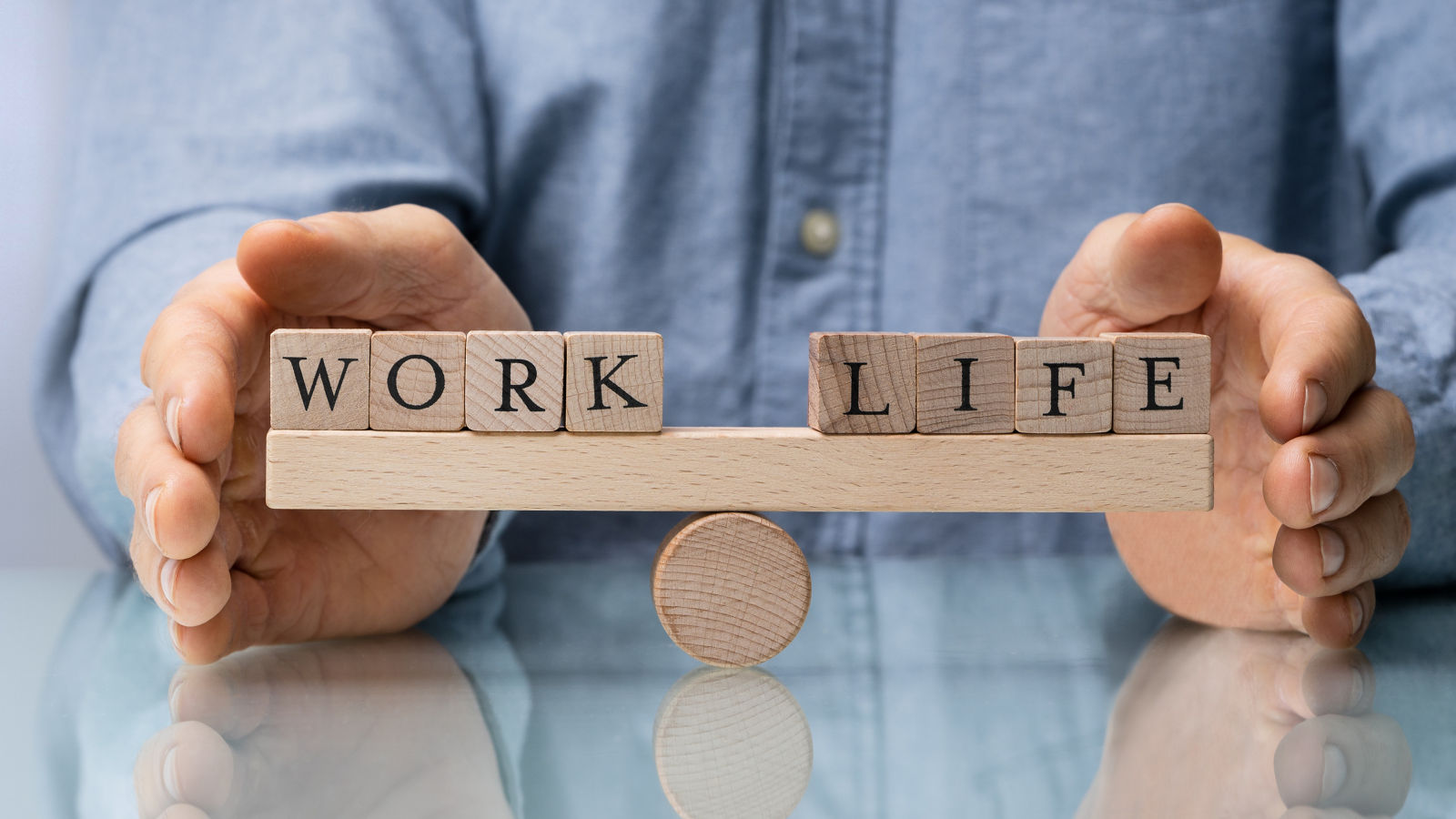 Close-up Of A Businessman's Hand Covering Balance Between Life And Work On Seesaw