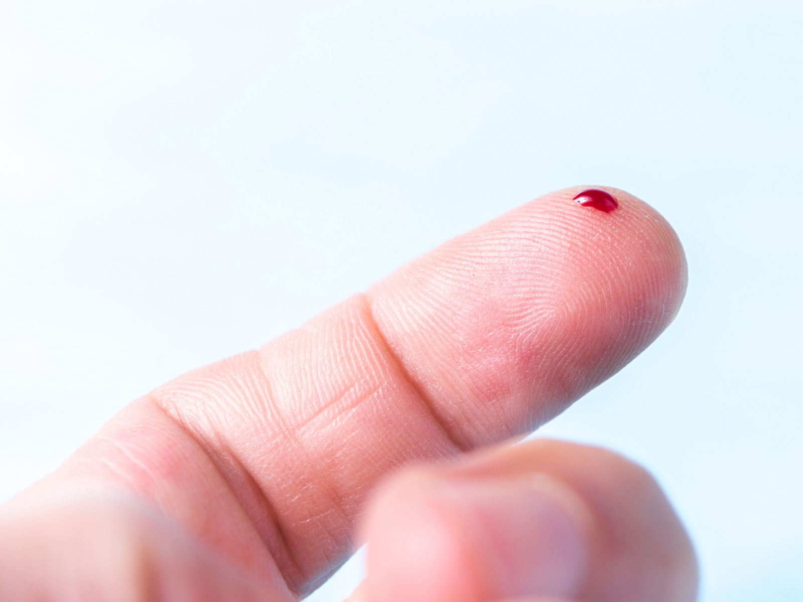 Zeigefinger in Nahaufnahme mit kleinem Bluttropfen
