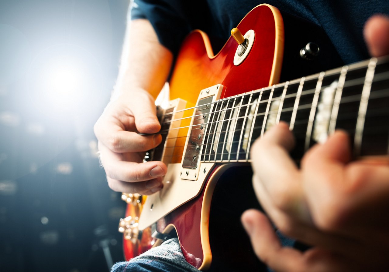 man playing on guitar, stage light, musical concert close up view