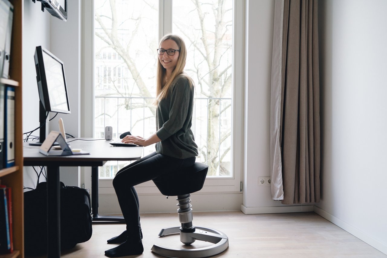 Eine junge Frau sitzt auf einem ergonomischen Stuhl im Homeoffice