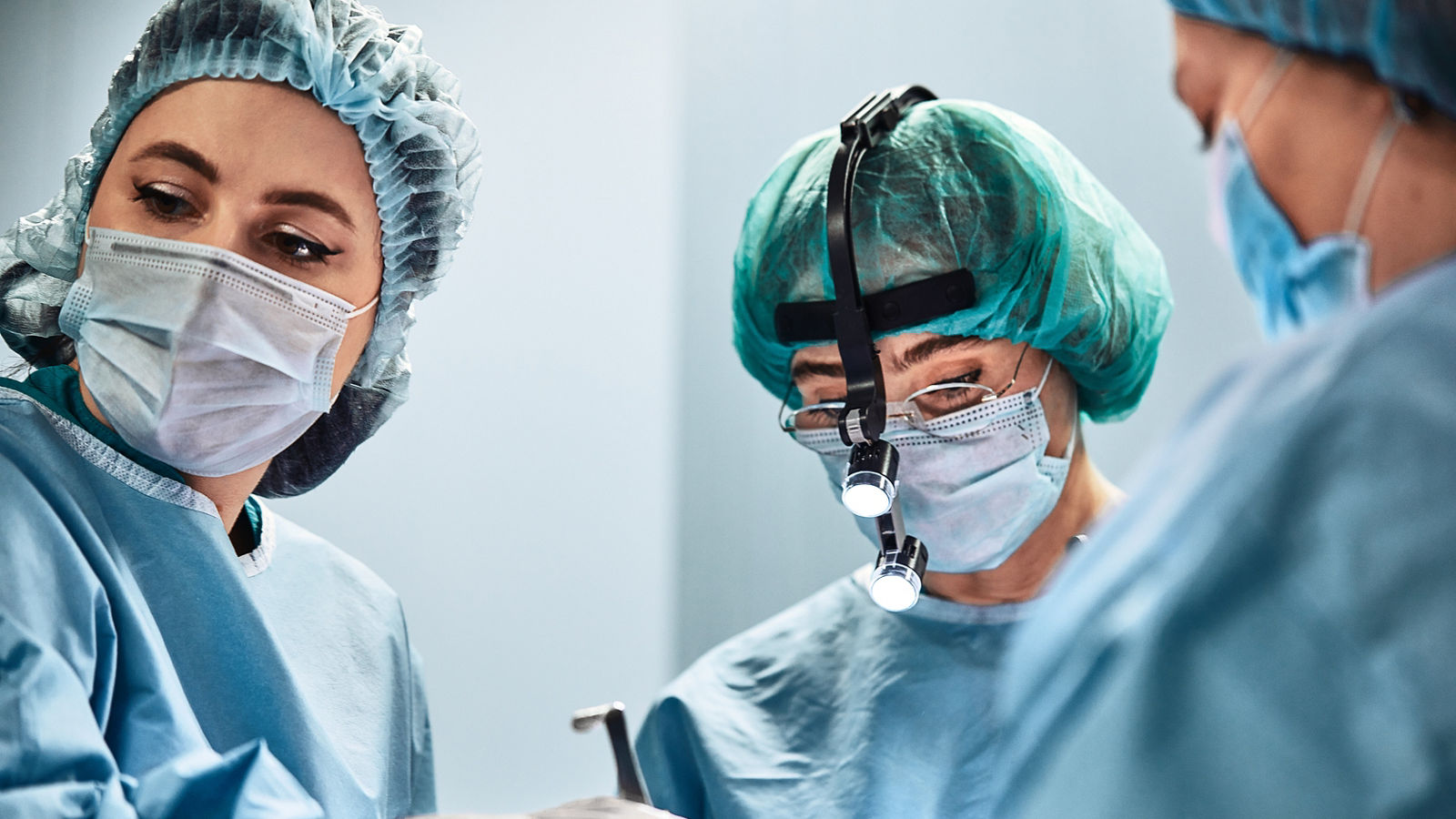 A surgeon s team in uniform performs an operation on a patient in the clinic of the center.