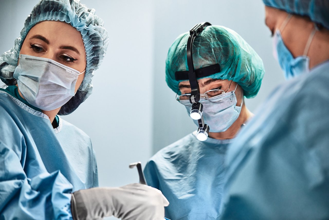 A surgeon s team in uniform performs an operation on a patient in the clinic of the center