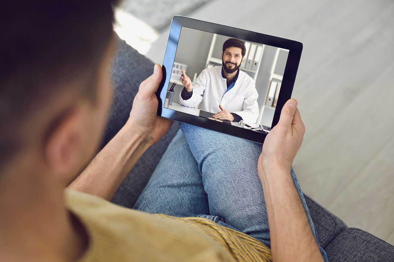 Online medical consultation for patients. Doctor man video call using laptop talks with male patient sitting on the sofa at home. Telemedicine concept virtual hospital medicine diagnosis symptoms prescription.