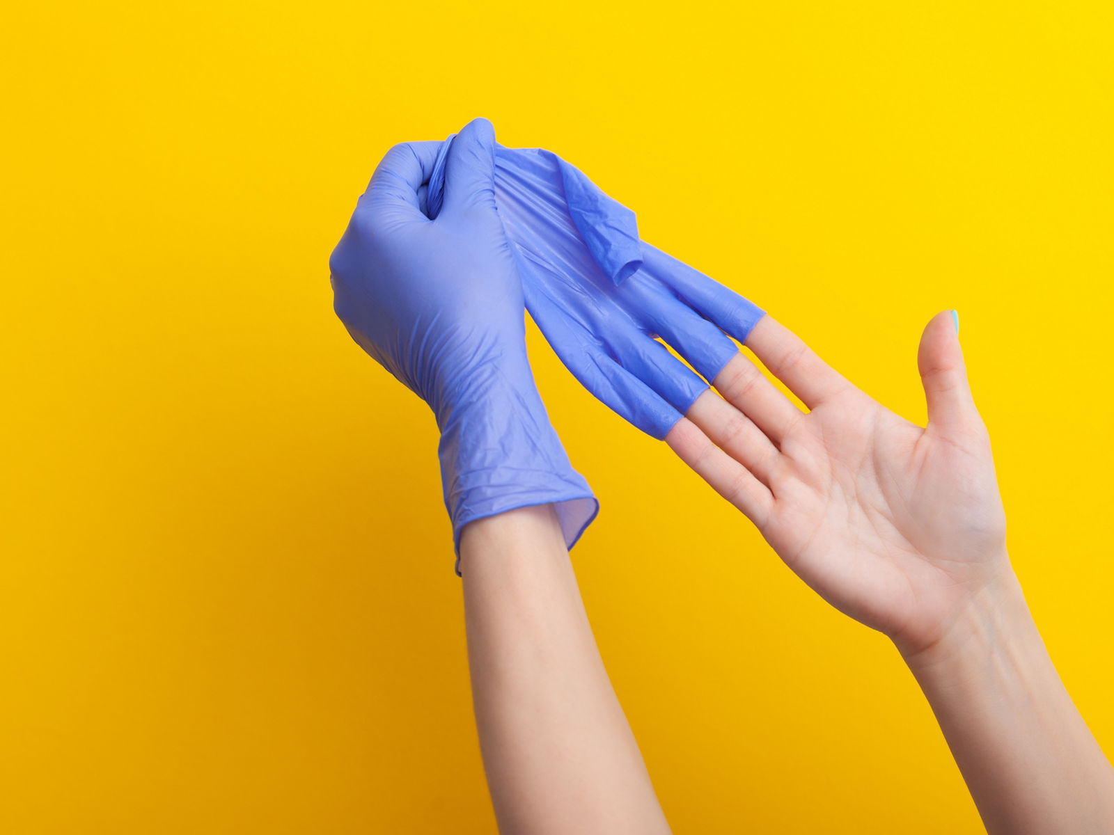 Ein bleuer unsteriler Gummihandschuh wird von der Hand abgestreift 
