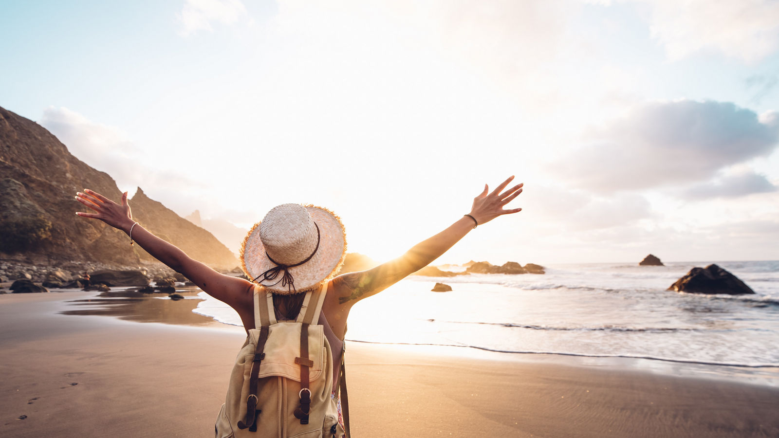 Happy woman with arms up enjoy freedom at the beach at sunset. Wellness, success, freedom and travel concept