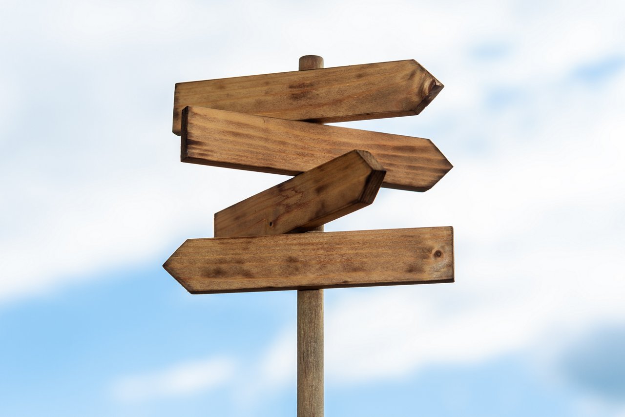 Wooden sign post isolated on blue sky with white clouds. Direction concept. Mock up, template