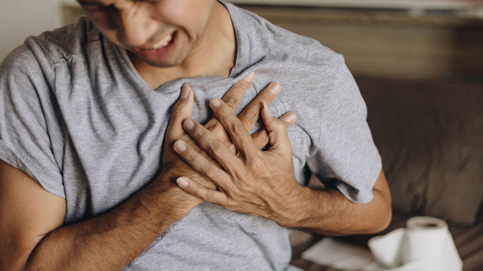 Young Asian man with chest pain in his bedroom