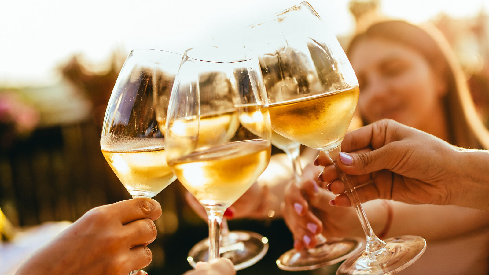 People clinking glasses with wine on the summer terrace of cafe or restaurant