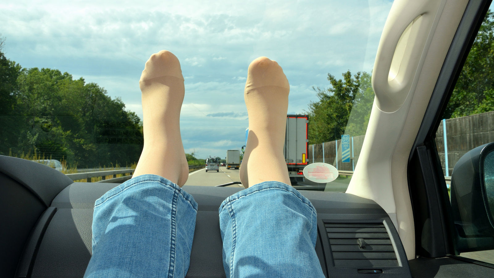 Legs in compression stockings rest on the car's torpedo. Concept for prevention of varicose veins and deep vein thrombosis during long journeys.,Legs in compression stockings rest on the car's torpedo. Concept