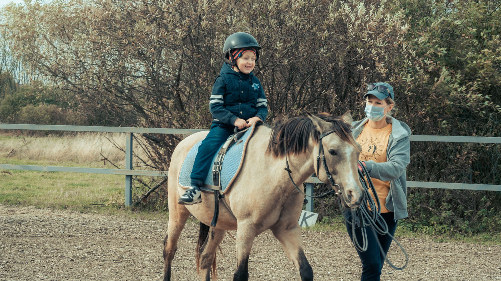 A child with special needs is riding with a close supervision teacher. This is a treatment called Hippotherapy, Life in the education age of disabled children, Happy disability kid concept. quarantine