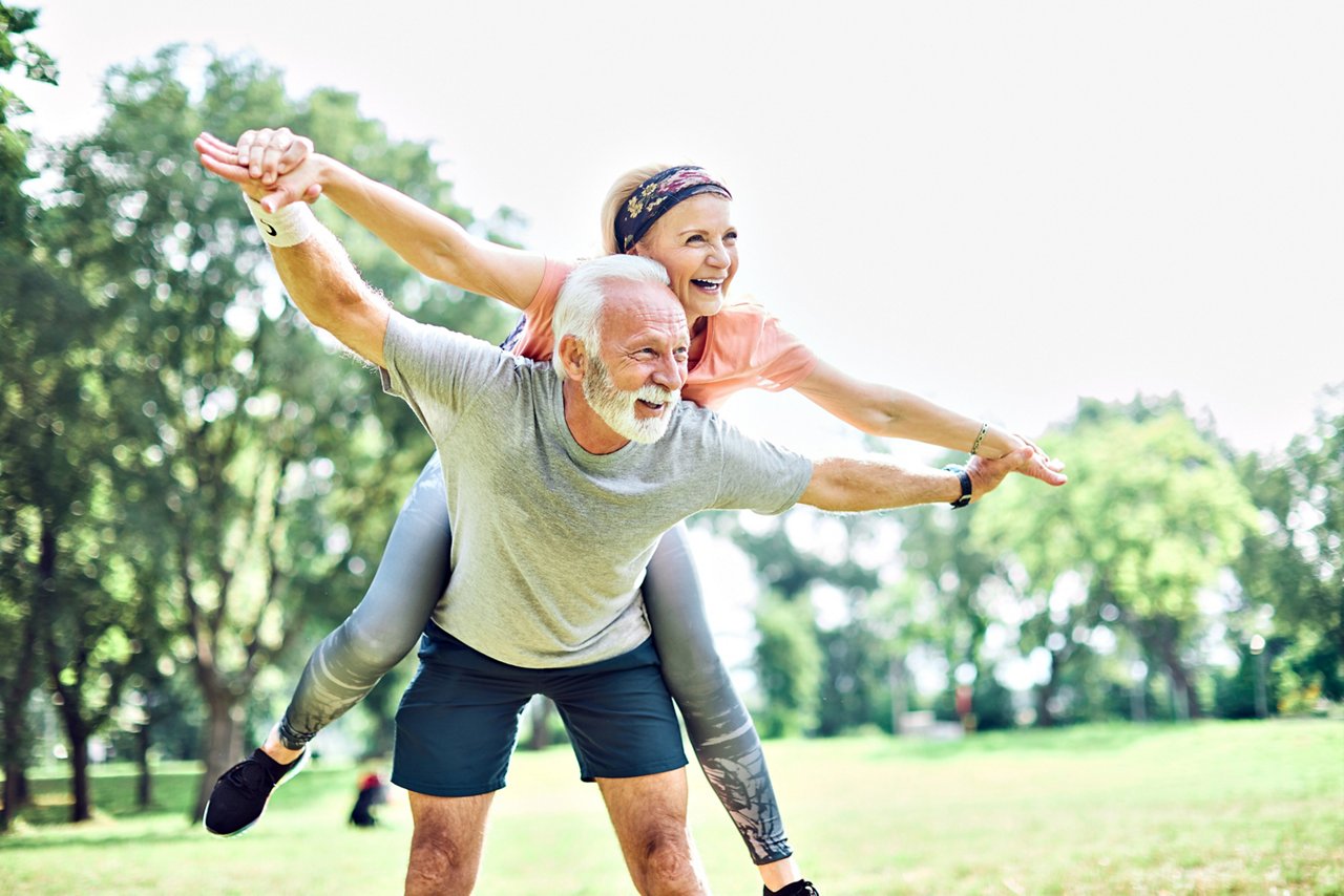 Smiling active senior couple having fun  together in the park