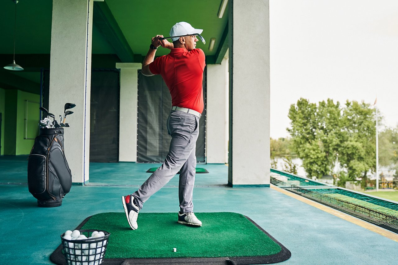 Männlicher Golfspieler übt seinen Abschlag