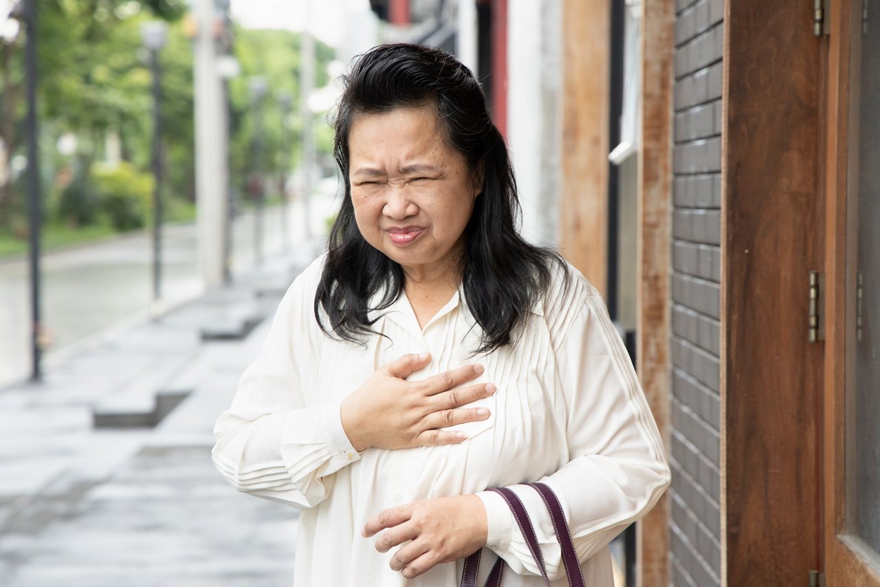 sick old senior woman suffering from GERD or acid reflux