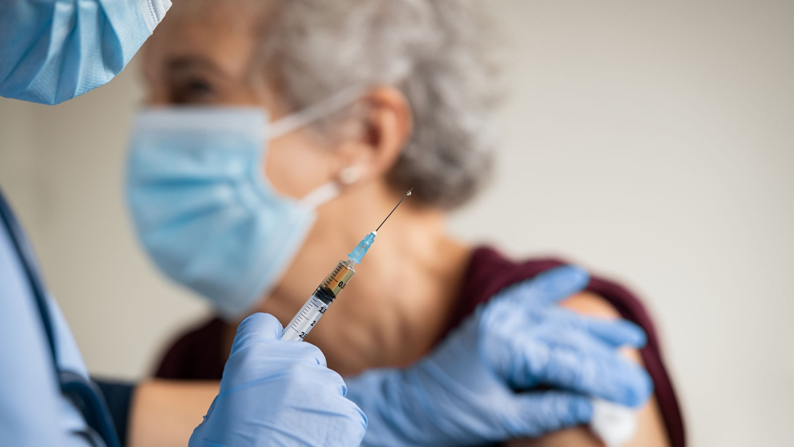 Doctor makes vaccination to senior woman with surgical mask