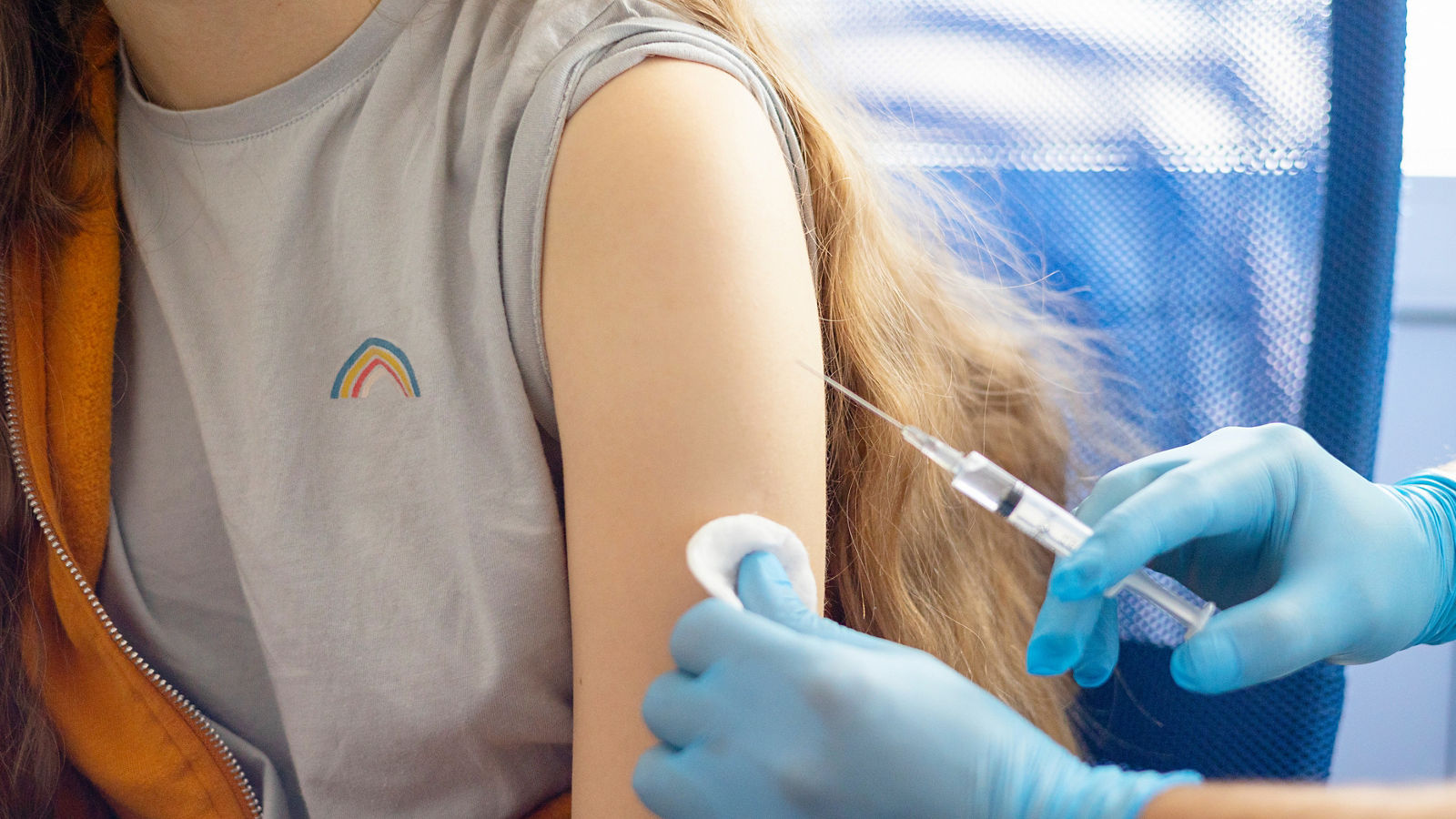 a doctor in gloves vaccinates a teenage girl