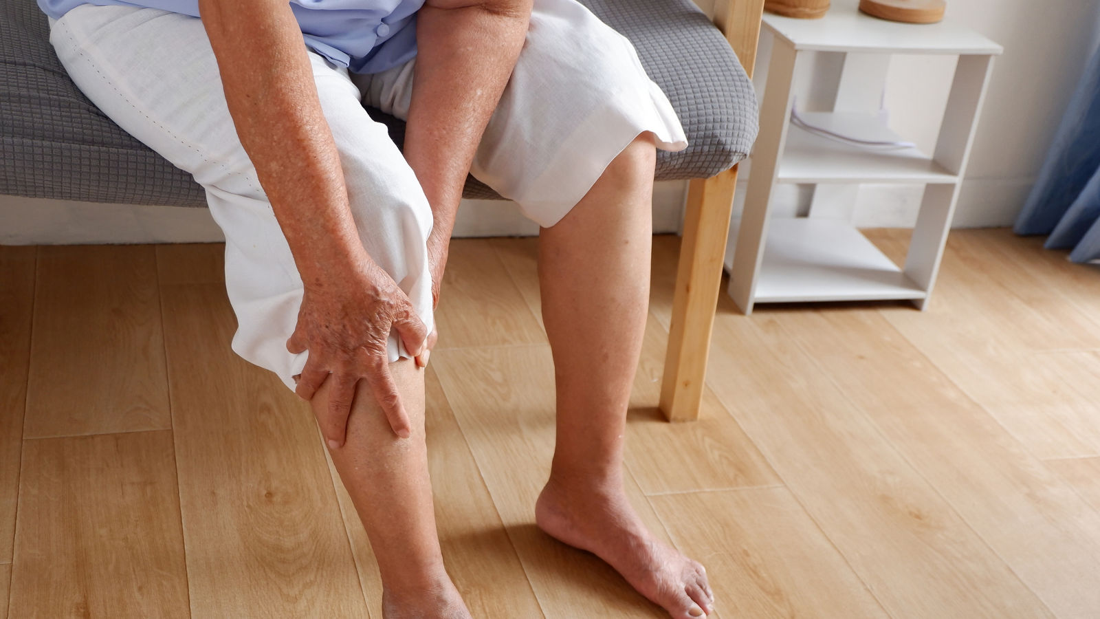 Elderly asian woman holding a leg that is painful from varicose veins or from osteoarthritis, Various illnesses of the elderly and good health concept.