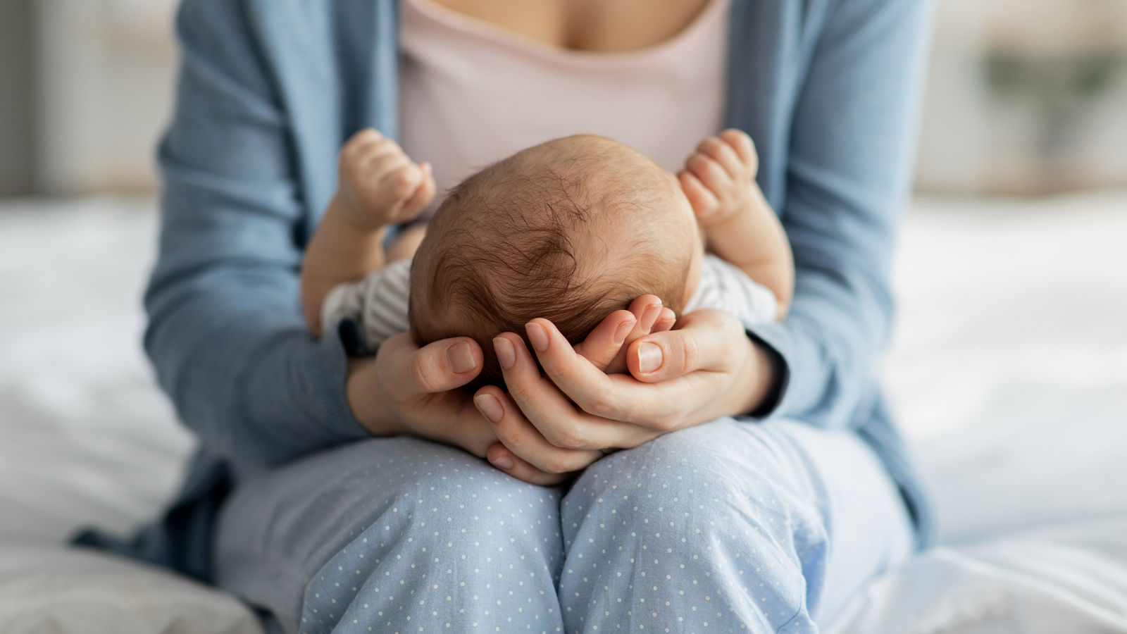 Mother Care. Unrecognizable mom holding newborn baby on her laps